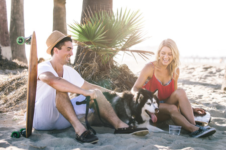 Couple having fun with their skates and playful huskyの写真素材