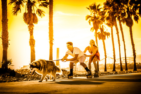 Couple having fun with their rollerskates and playful huskyの写真素材