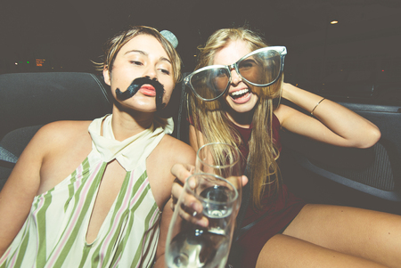 Party girls celebrate in Hollywood drinking champagne on a covertible car