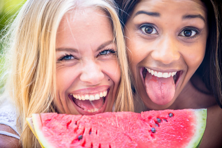 Two pretty girlfriends eating a slice of watermelonの写真素材