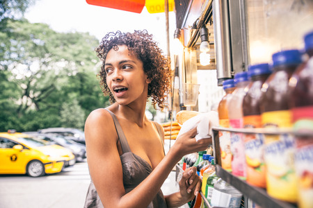 Pretty woman buying a hot dog in a kiosk in New Yorkの写真素材