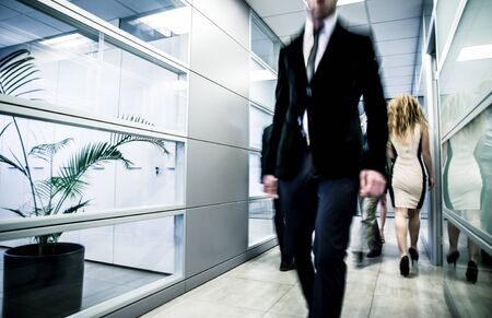 Business office daily life. Blurred people walking in an office corridorの写真素材