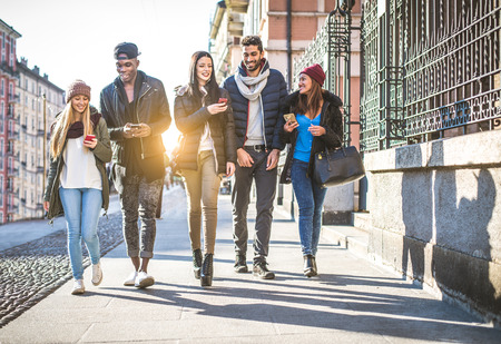 Group of multi-ethnic friends walking on the streets and smiling - Young people having fun outdoorsの写真素材
