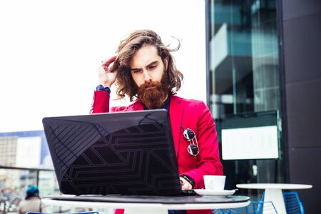Young hipster man working at pc laptop in a cafè outdoorsの写真素材