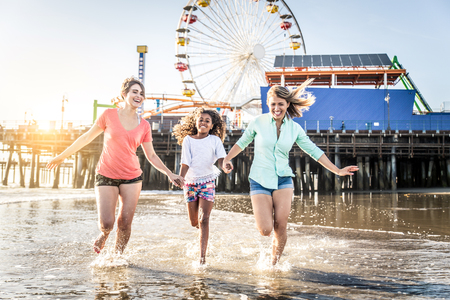 Lesbians mothers with adopted child - Happy homosexual family playing with her daughterの写真素材