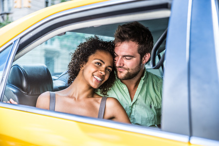 Interracial couple driving on a taxi in Manhattan - Tourists sightseeing New York on a yellow cabの写真素材