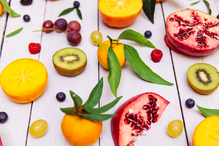 Mix of colored fruits on white wooden background - Composition of tropical and mediterranean fruitsの写真素材