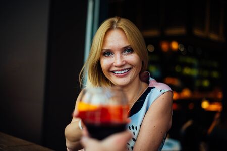 Cheerful couple drinking aperitif in a cocktail bar and having a pleasant conversationの写真素材