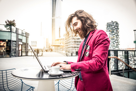 Young hipster man working at pc laptop in a cafè outdoorsの写真素材