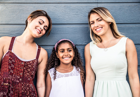 Lesbians mothers with adopted child - Happy homosexual family playing with her daughterの写真素材