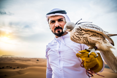 Arabian man walking  in the desert at sunriseの写真素材