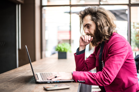 Young hipster man working at pc laptop in a cafèの写真素材