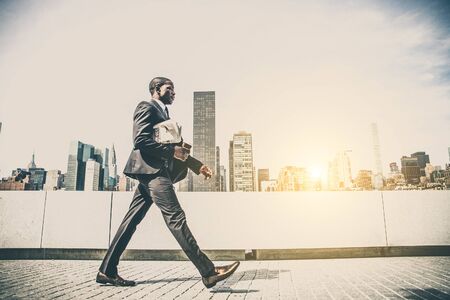 Confident businessman. Successful young man in full suit walking to office with cityscape in the...