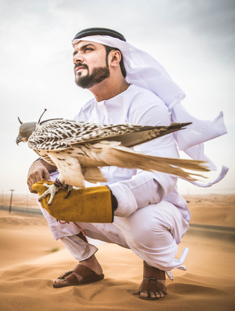 Arabian man walking  in the desert at sunrise