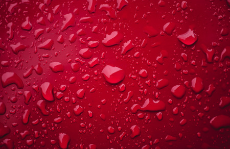 Water drops macro on a red surfaceの写真素材