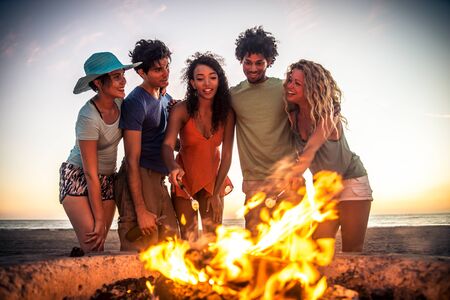 Multicultural group of friends partying on the beach - Young people celebrating during summer...