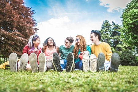 Group of multicultural people having fun while bonding in a park outdoors