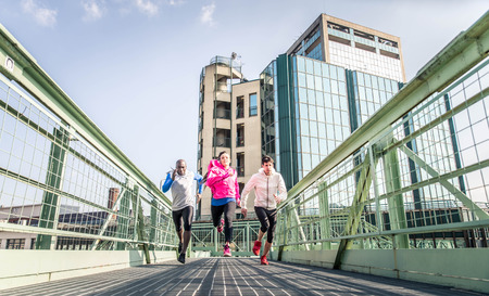 Three runners sprinting outdoors - Sportive people training in a urban area - healthy lifestyle and sport conceptsの写真素材