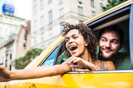 Interracial couple driving on a taxi in Manhattan - Tourists sightseeing New York on a yellow cabの写真素材