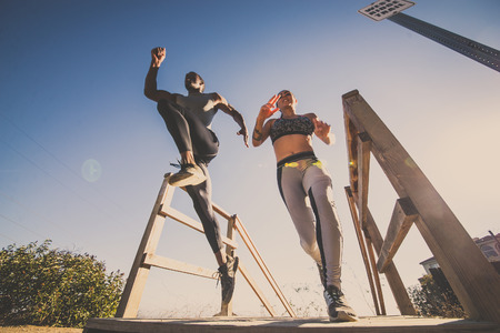 Sportive people jumping over an obstacle - Runners training outdoorsの写真素材