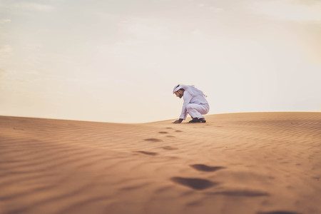 Arabian man walking  in the desert at sunriseの写真素材