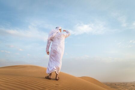 Arabian man walking  in the desert at sunriseの写真素材