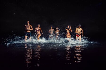 Group of friends taking night bath in the oceanの写真素材