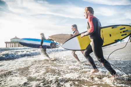 Group of friends going to surf at the beachの写真素材