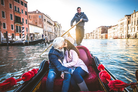 Couple of lovers on vacation in Venice, Italy - Tourists having a trip on a venetian gondolaの写真素材