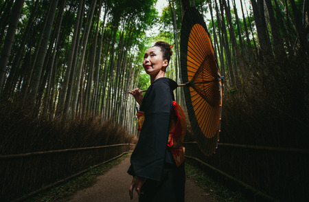 Beautiful japanese senior woman walking in the bamboo forestの写真素材
