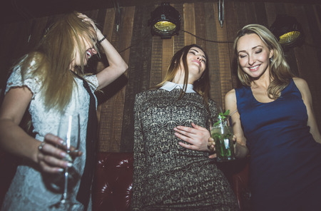 Party girls in a restaurant celebrating with drinks and champagneの写真素材