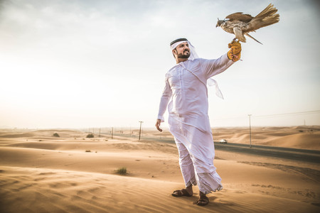 Arabian man walking  in the desert at sunriseの写真素材