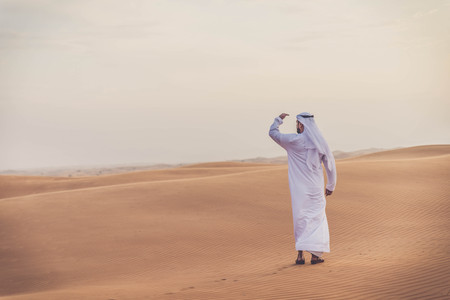 Arabian man walking  in the desert at sunriseの写真素材