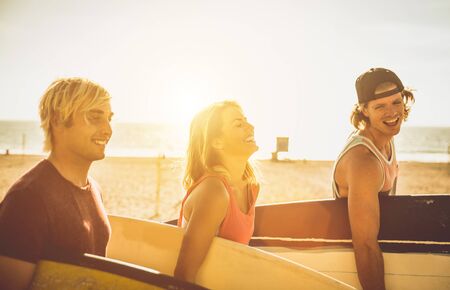 Three surfers walking on the beach carrying their boards