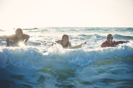 Three surfers practicing in the oceanの写真素材