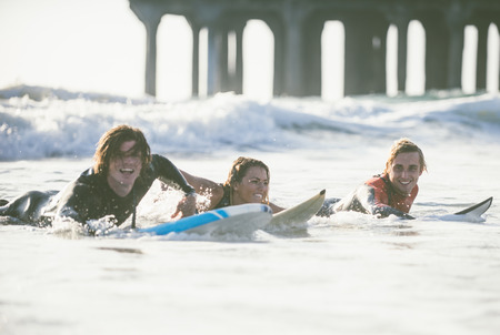 Three surfers practicing in the oceanの写真素材