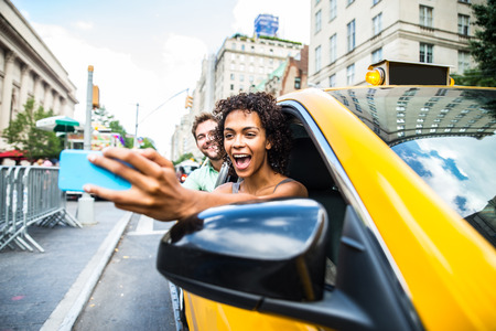 Interracial couple driving on a taxi in Manhattan - Tourists sightseeing New York on a yellow cab