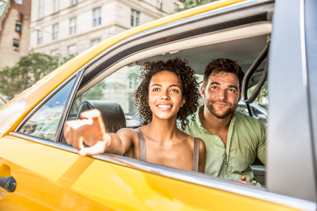 Interracial couple driving on a taxi in Manhattan - Tourists sightseeing New York on a yellow cabの写真素材