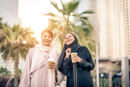 Arabic women shopping outdoors in Dubai - Girls with traditional arabian dress having funの写真素材