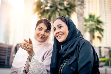 Arabic women shopping outdoors in Dubai - Girls with traditional arabian dress having funの写真素材