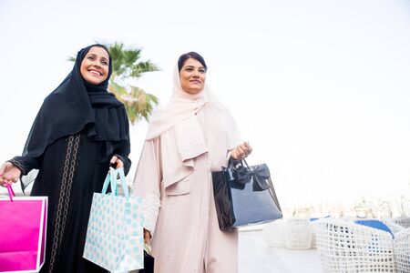Arabic women shopping outdoors in Dubai - Girls with traditional arabian dress having funの写真素材