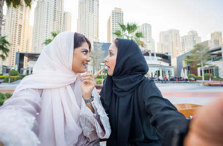 Arabic women shopping outdoors in Dubai - Girls with traditional arabian dress having funの写真素材
