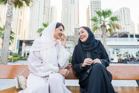 Arabic women shopping outdoors in Dubai - Girls with traditional arabian dress having funの写真素材