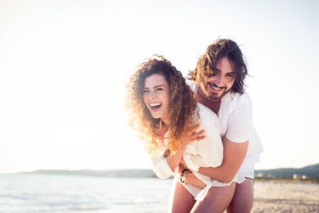 Couple strolling at the beach and smiling - Young adults enjoying summer holidays on a tropical islandの写真素材
