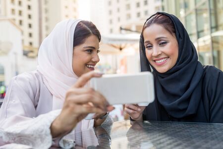 Arabic women shopping outdoors in Dubai - Girls with traditional arabian dress having funの写真素材