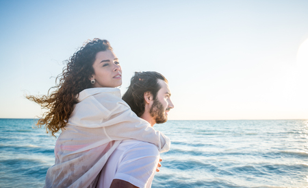 Couple strolling at the beach and smiling - Young adults enjoying summer holidays on a tropical islandの写真素材