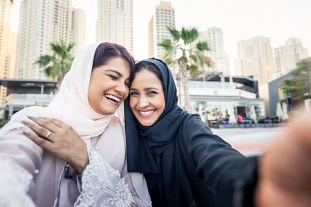 Arabic women shopping outdoors in Dubai - Girls with traditional arabian dress having funの写真素材