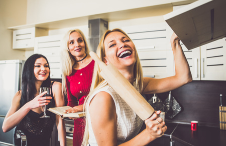 Three woman friends having fun in the kitchen and preparing foodの写真素材