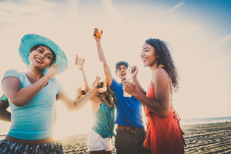 Multicultural group of friends partying on the beach - Young people celebrating during summer vacation, summertime and holidays conceptsの写真素材