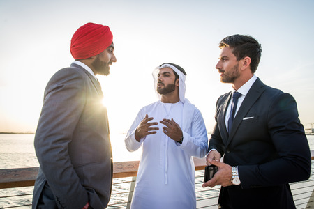Multiethnic business team meeting outdoors - Three businessmen talking about business on a formal meetingの写真素材